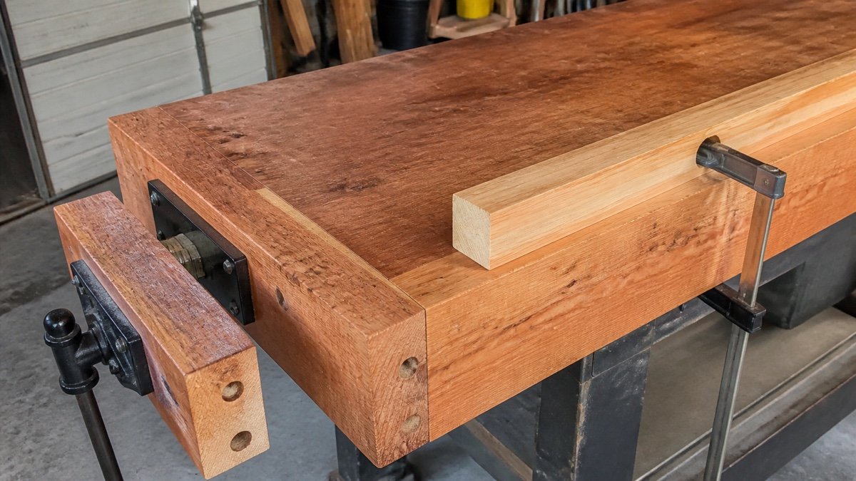 Wood workbench edge with a board secured by bench clamps