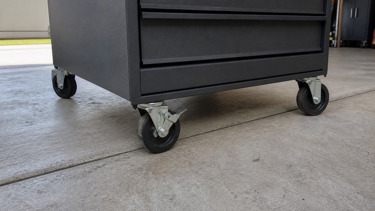 Large casters on a loaded rolling tool chest crossing a concrete garage joint